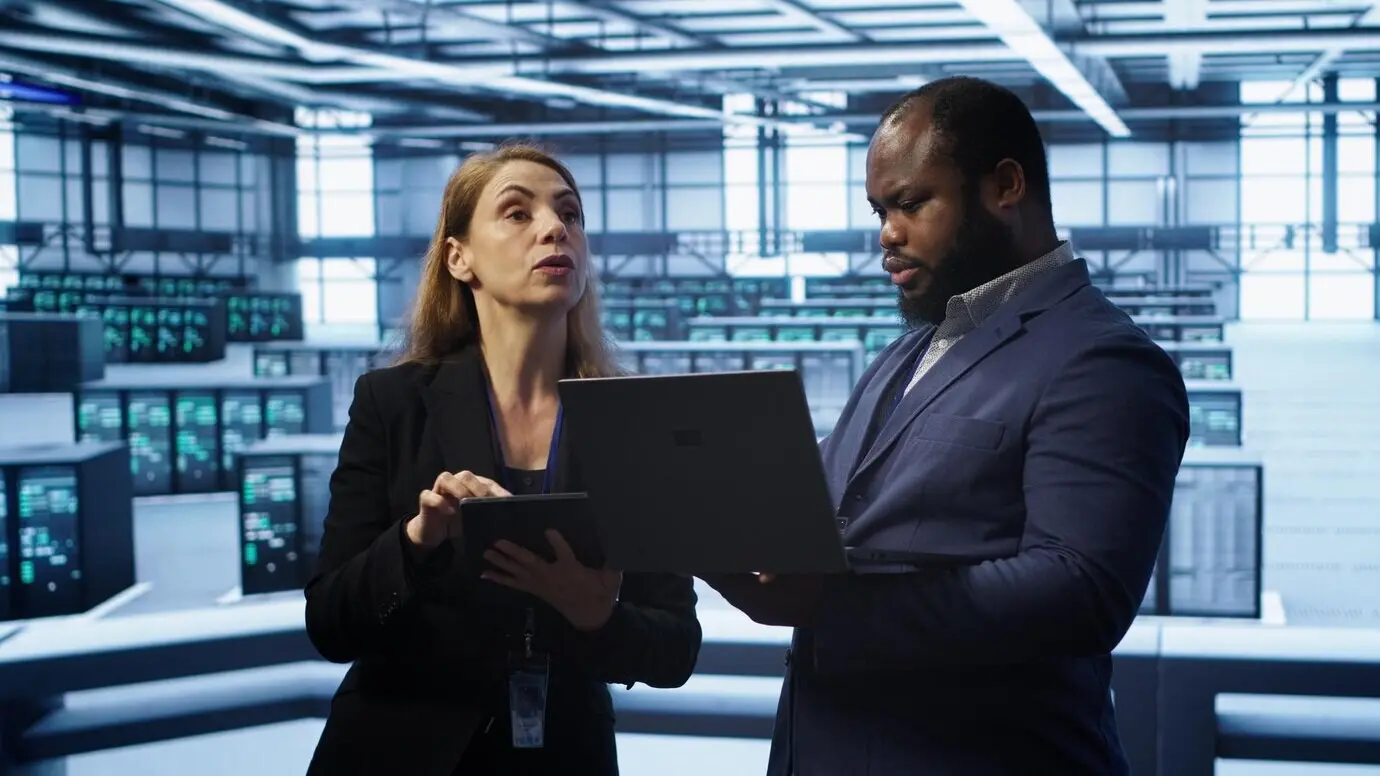 Supervisore in una server farm che sovrintende a un ingegnere mentre risolve problemi di rete.